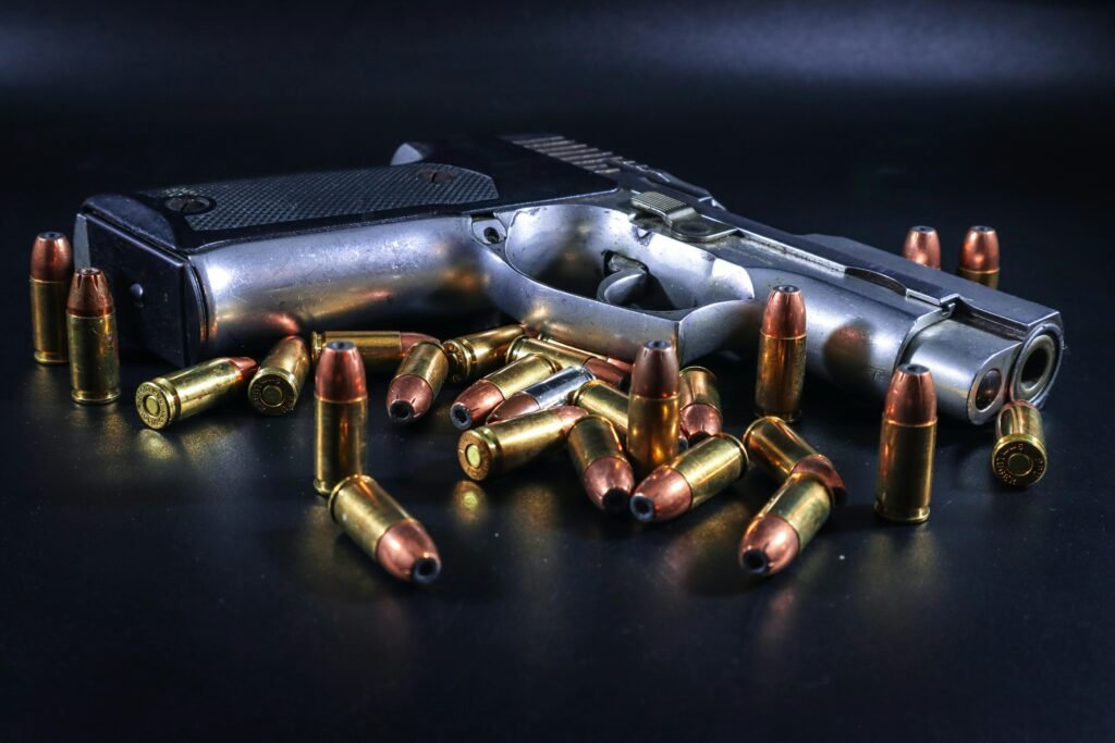 A pistol surrounded by brass bullets on a black background, ideal for weaponry-themed projects.